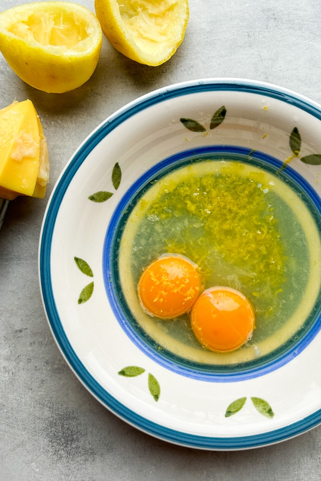 Egg yolks with lemon zest and lemon juice in a bowl