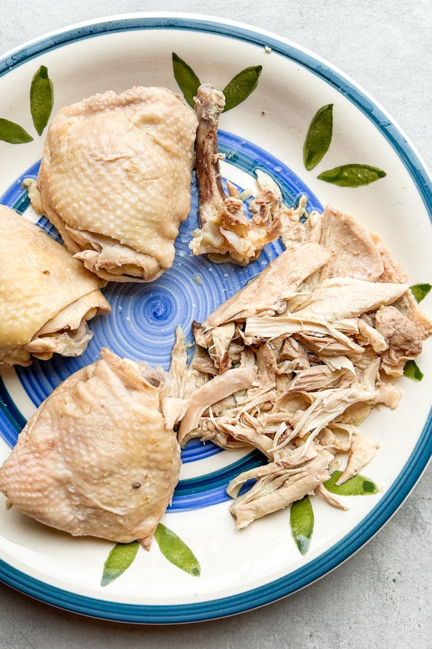 boiled chicken thighs being shredded for avgolemono soup